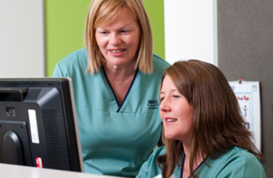 two people in NHS uniforms looking at a computer