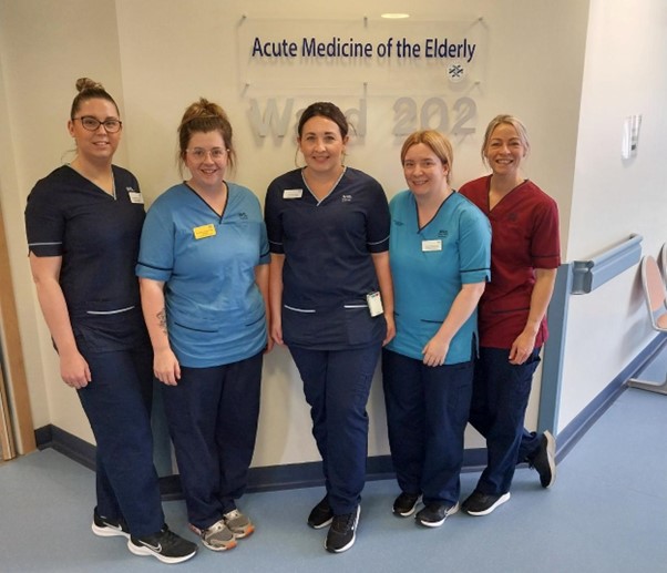 Five members in of staff in uniform outside the  Acute Medicine of the Elderly Ward of the Royal Infirmary, Edinburgh. 