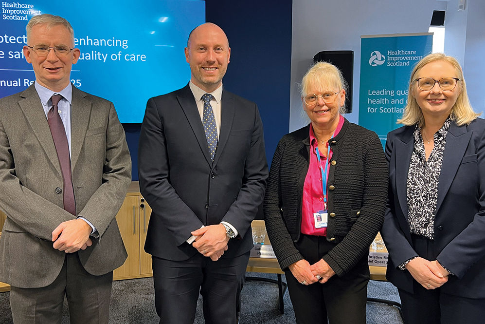 Four people standing before a screen at the Healthcare Improvement Scotland (HIS) annual review. Left to right - Robbie Pearson, Chief Executive; Neil Gray, Cabinet Secretary for Health and Social care; Evelyn McPhail, Chairman ;and Christine McLaughlin, Chief Operating Officer & Deputy Chief Executive, NHS Scotland , DG Health and Social Care