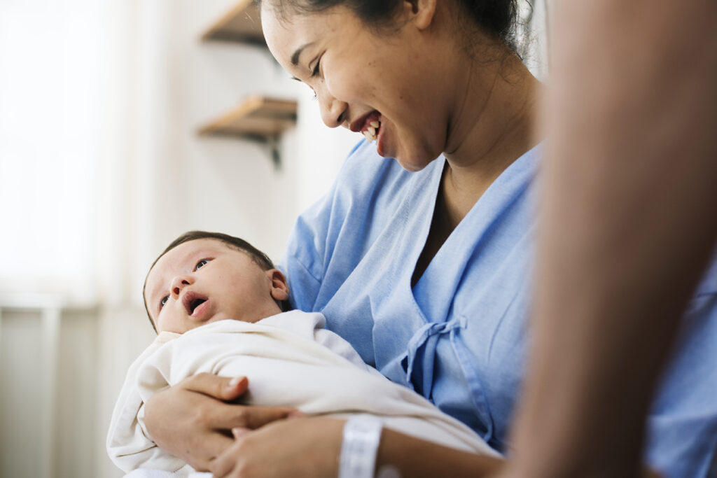 A woman holding and smiling at a newborn baby.
