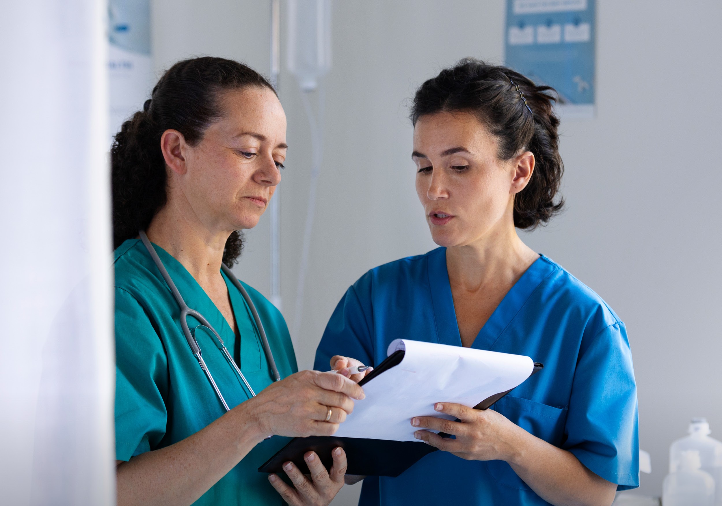 Two people in scrubs collaborate while looking at a document