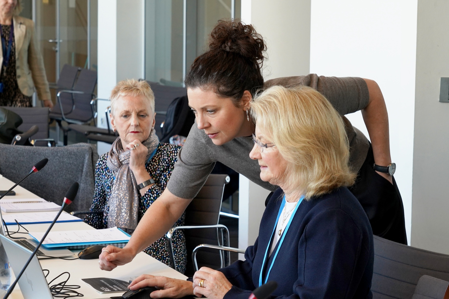 Three people collaborate at a desk.